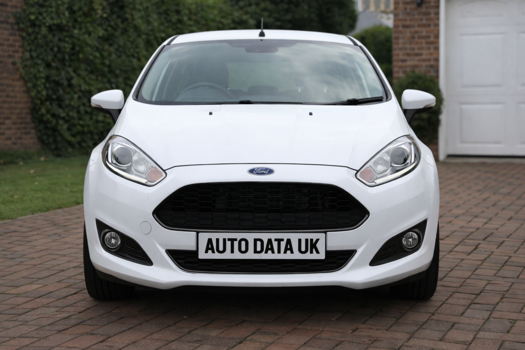 White Ford Fiesta parked on a residential driveway with Auto Data UK number plate